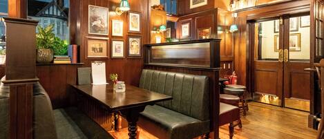 Una habitación acogedora con paneles de madera, un banco, una mesa y cuadros en las paredes.