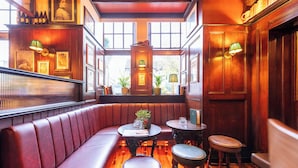 Een gezellig restaurant met houten wanden, een rode lederen zithoek en uitzicht op de straat door grote ramen.