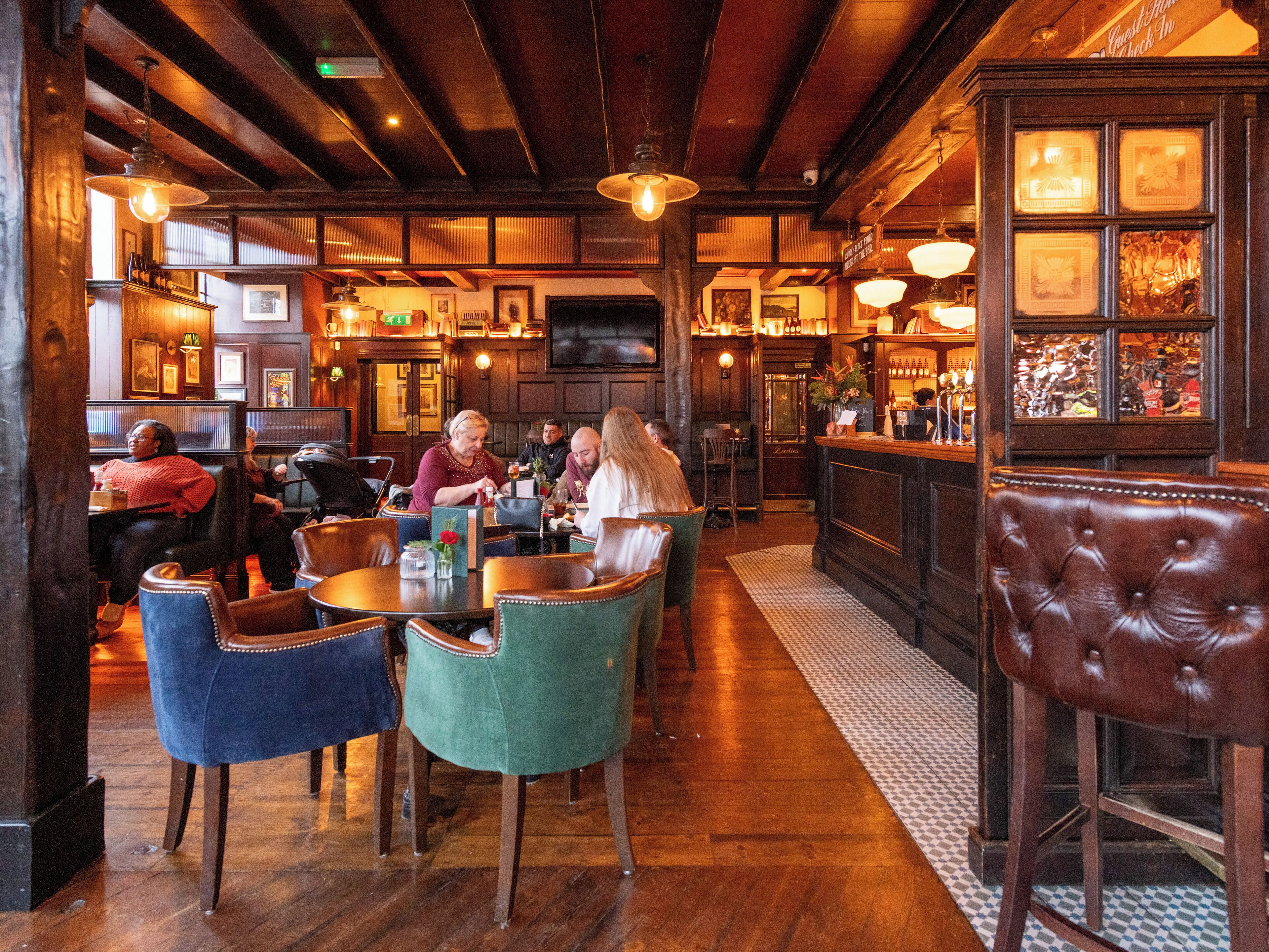 A cozy restaurant with wooden floors and a bar area.