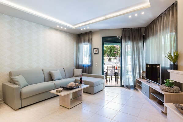 A modern living room with a sofa, coffee table, TV stand, and curtains.