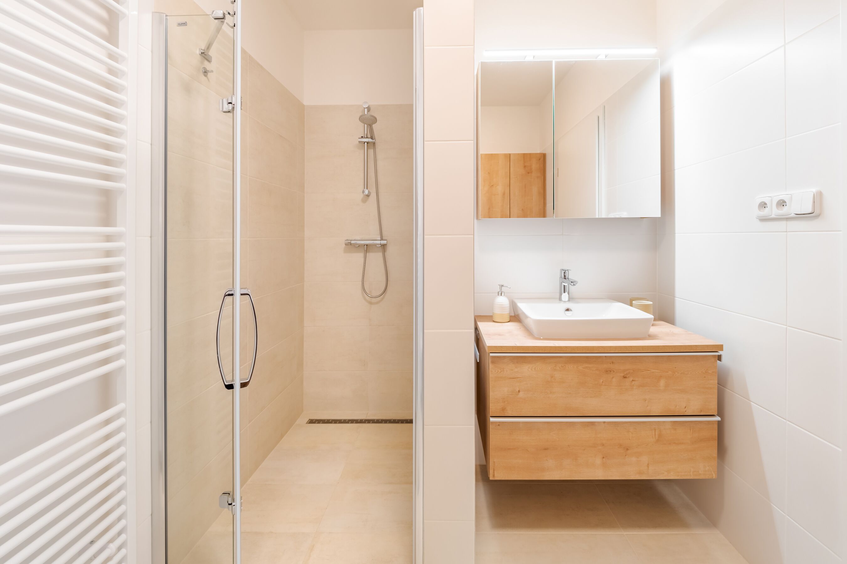 A modern bathroom with a glass shower enclosure, a wooden vanity with a sink, and a mirror above the vanity.