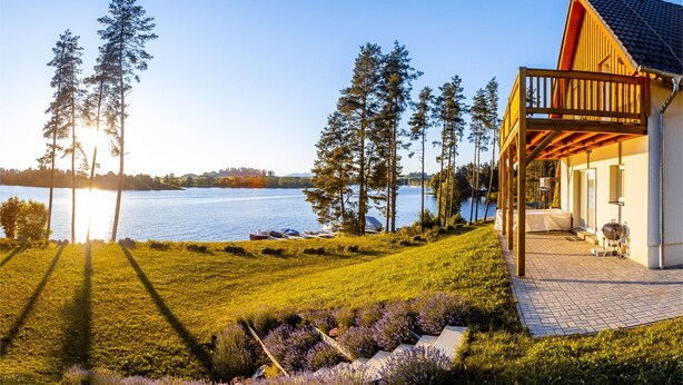 A lakeside property with a wooden deck, a covered patio, and a view of the lake. - Lakeside Village Větrník (Frymburk)