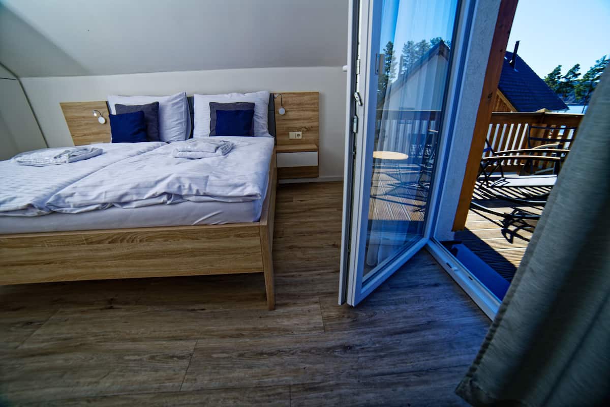 A bedroom with a wooden bed, a nightstand, and a sliding glass door leading to an outdoor patio.