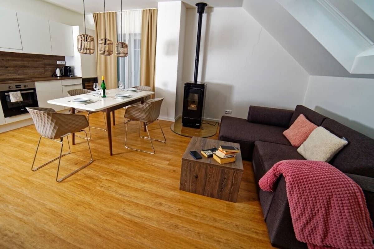 A modern living room with a sofa, a coffee table, and a dining area with chairs and a table.