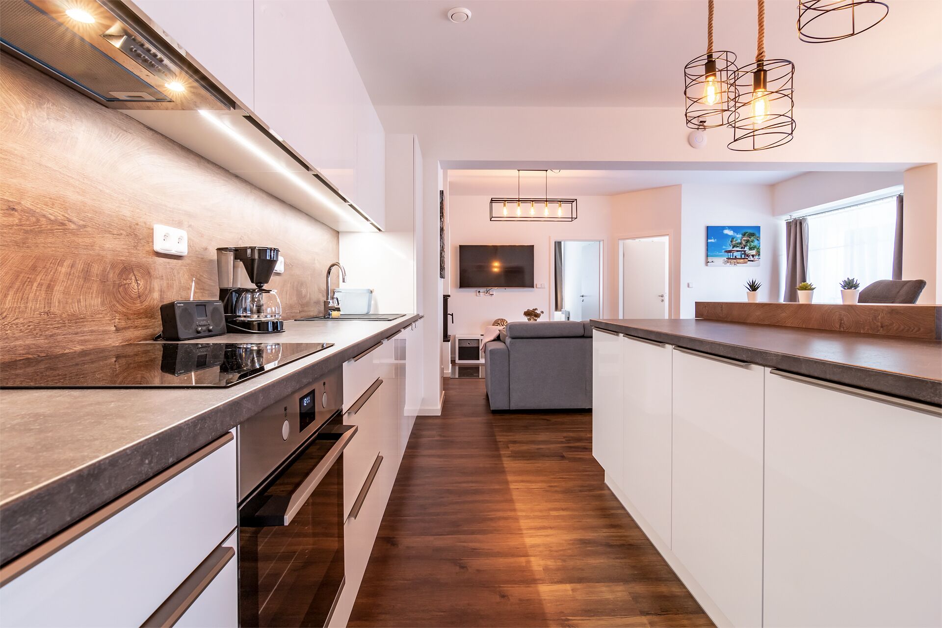 A modern kitchen with a central island, built-in appliances, and pendant lighting.