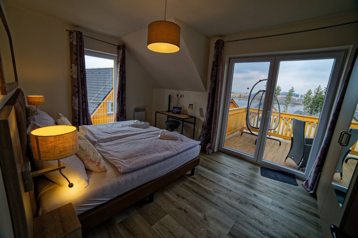 A bedroom with a bed, bedside lamp, and a desk with a computer.