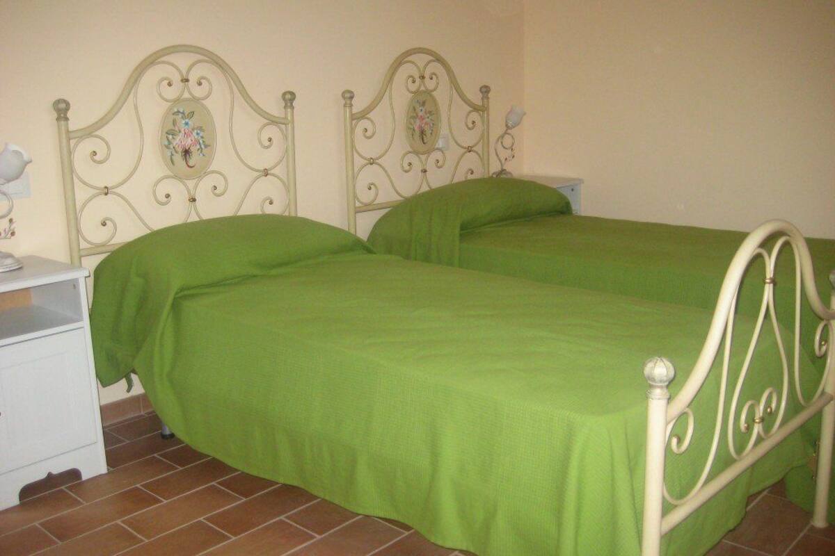 Ein Schlafzimmer mit zwei Einzelbetten, einem Nachttisch und einer Wandlampe.