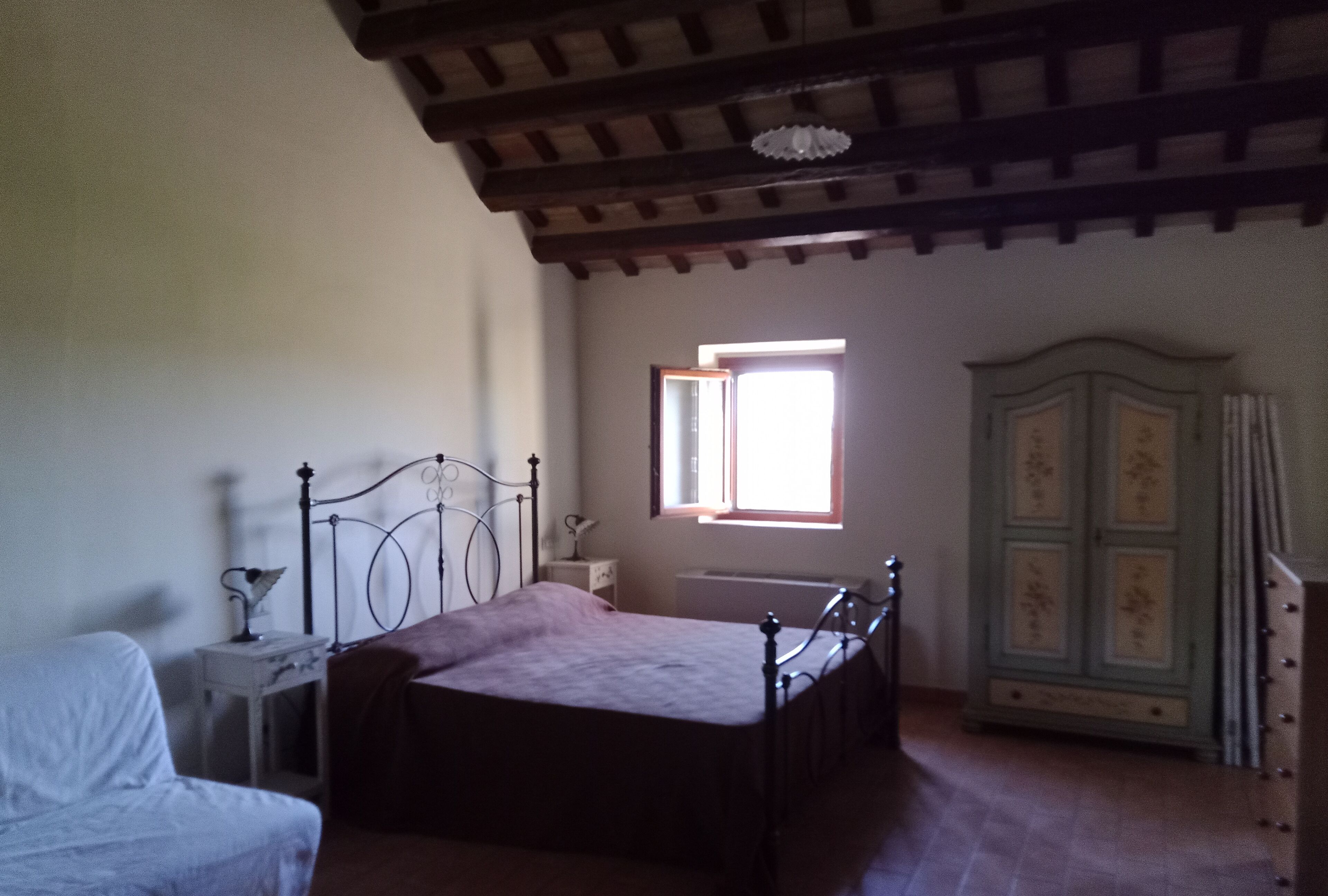 Une chambre à coucher avec un lit, une table de chevet, une armoire et une fenêtre.