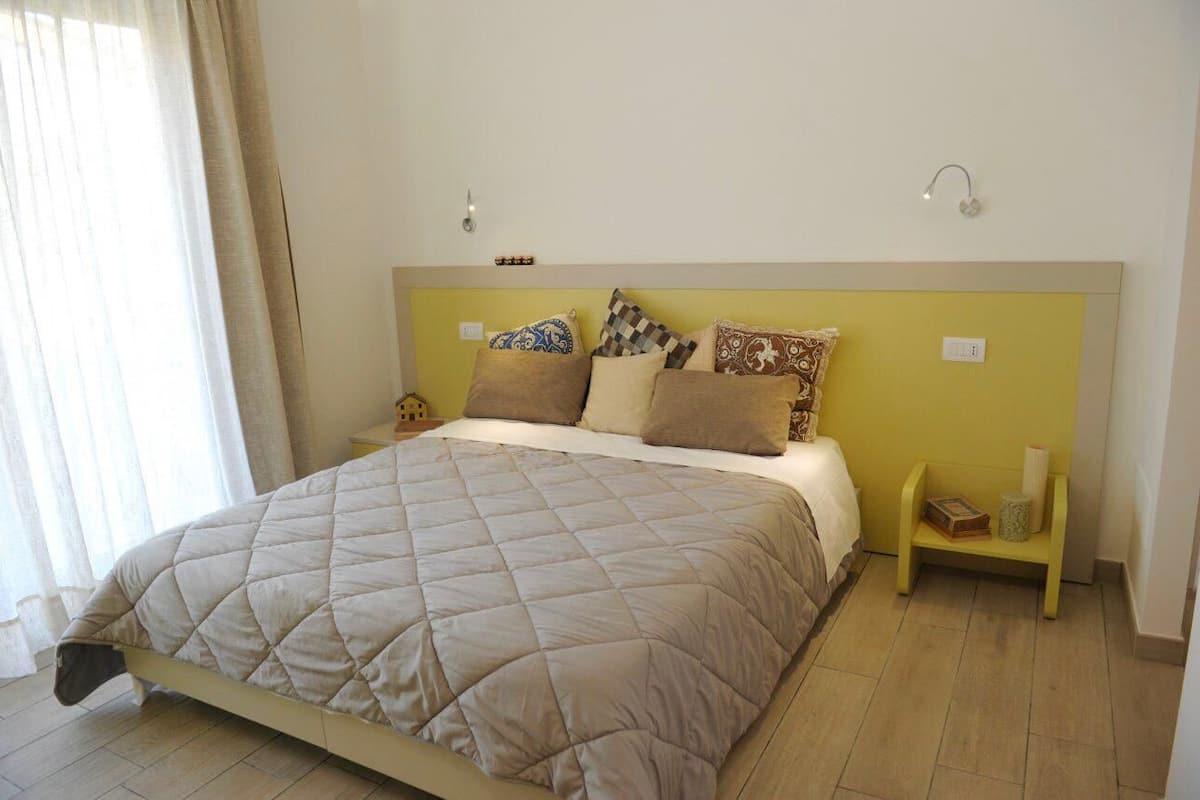 Une chambre à coucher avec un lit, des oreillers, des tables de chevet et une fenêtre avec des rideaux.