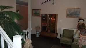 A living room with a large plant, a wooden cabinet, and two chairs. - Domäne-Badetz (Zerbst/Anhalt)