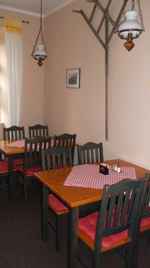 A dining area with a wooden table and chairs, a checkered tablecloth, and two hanging lamps. - Domäne-Badetz (Zerbst/Anhalt)
