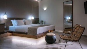Un dormitorio moderno con una cama grande, lámparas de noche, una mesita redonda con dos vasos y un espejo amplio.