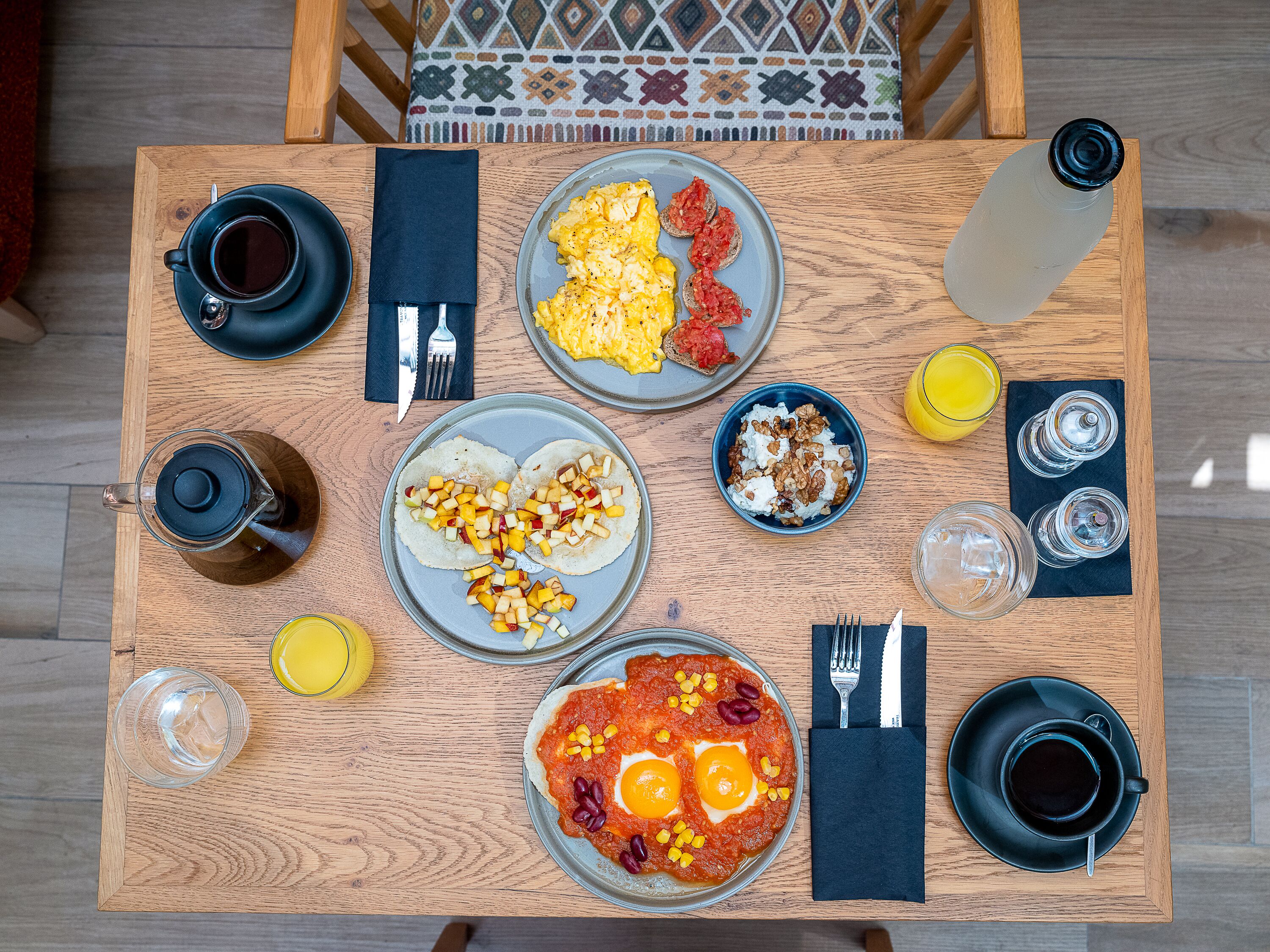 A breakfast table with various dishes, drinks, and utensils.