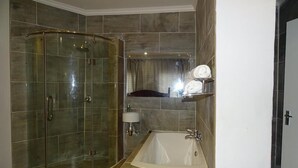 Ein modernes Badezimmer mit einer Duschkabine, einer freistehenden Badewanne und einem Waschtisch mit Spiegel.