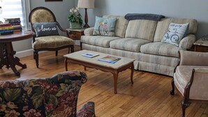 A living room with a sofa, armchairs, a coffee table, and a bookshelf. - Roomy 1896 Victorian Farmhouse Farm Stay in Lee Virginia (Dryden)