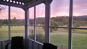 A room with large windows overlooking a rural landscape with fields and trees, and a chair is visible inside. - Roomy 1896 Victorian Farmhouse Farm Stay in Lee Virginia (Dryden)