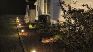 A white house with a front porch, a small garden with plants, and a pathway lit by ground lights. - Roomy 1896 Victorian Farmhouse Farm Stay in Lee Virginia (Dryden)
