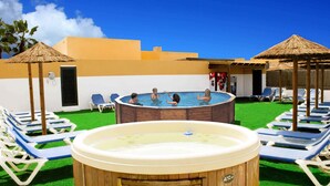 A pool area with lounge chairs, a hot tub, and umbrellas. - GBH Volcanic Beach (La Oliva)