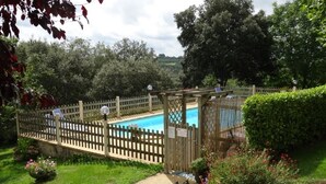 Ein Poolbereich mit Holzzaun, einer Pergola und einem Garten mit verschiedenen Pflanzen und Blumen.