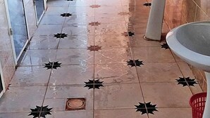 A tiled floor with star patterns and a red basket near a sink.