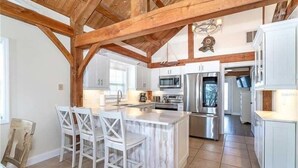 A kitchen with a central island, white cabinetry, and a wooden ceiling. - Waterfront, Gulf View, Pool is now open tennis, pickleball, kayaks, SUP, dock (Placida)
