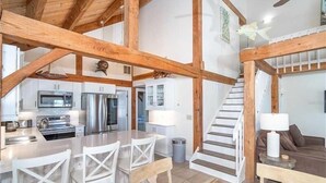 A spacious kitchen with modern appliances, a dining area with white chairs, and a staircase leading to an upper level. - Waterfront, Gulf View, Pool is now open tennis, pickleball, kayaks, SUP, dock (Placida)
