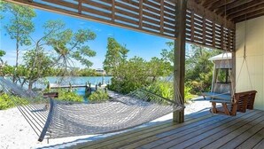 A wooden deck with a hammock and a swing chair overlooking a pool and lush greenery. - Waterfront, Gulf View, Pool is now open tennis, pickleball, kayaks, SUP, dock (Placida)