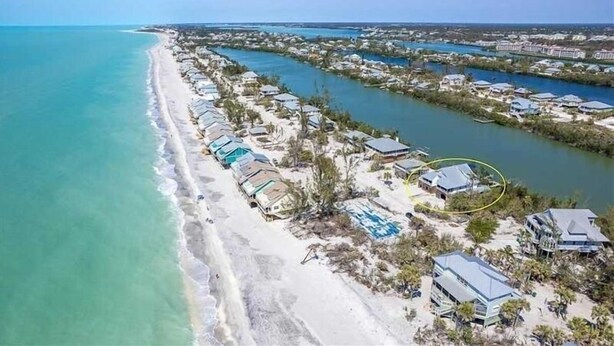 An aerial view of a coastal resort with beachfront properties, a marina, and a clear blue sky. - Waterfront, Gulf View, Pool is now open tennis, pickleball, kayaks, SUP, dock (Placida)
