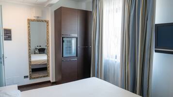 A hotel room with a large bed, a wardrobe, a mirror, a television, and a window with curtains.