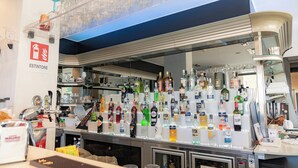 A bar area with a variety of liquor bottles and glasses displayed on shelves. - Hotel Napoleon (Melissa)