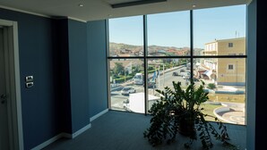 A room with a large window offering a view of a cityscape and a road. - Hotel Napoleon (Melissa)