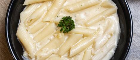Un plato de pasta con guarnición, sobre una superficie de madera.