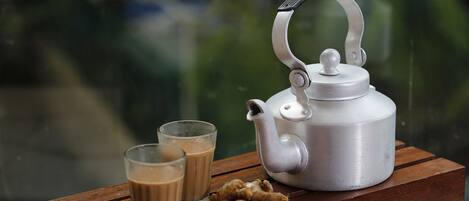 A silver teapot with a handle on a wooden table.