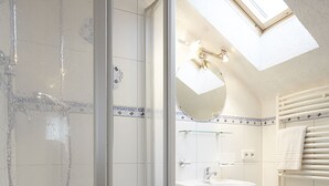 Une salle de bain moderne avec une douche à parois de verre, un lavabo, un miroir et un porte-serviettes.