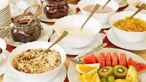 Une table mise pour le petit-déjeuner avec des bols de céréales, de yaourt et des fruits.