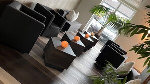 A modern lounge area with sofas, a coffee table, and potted plants. - Hotel Schlafplatz (Rodgau)