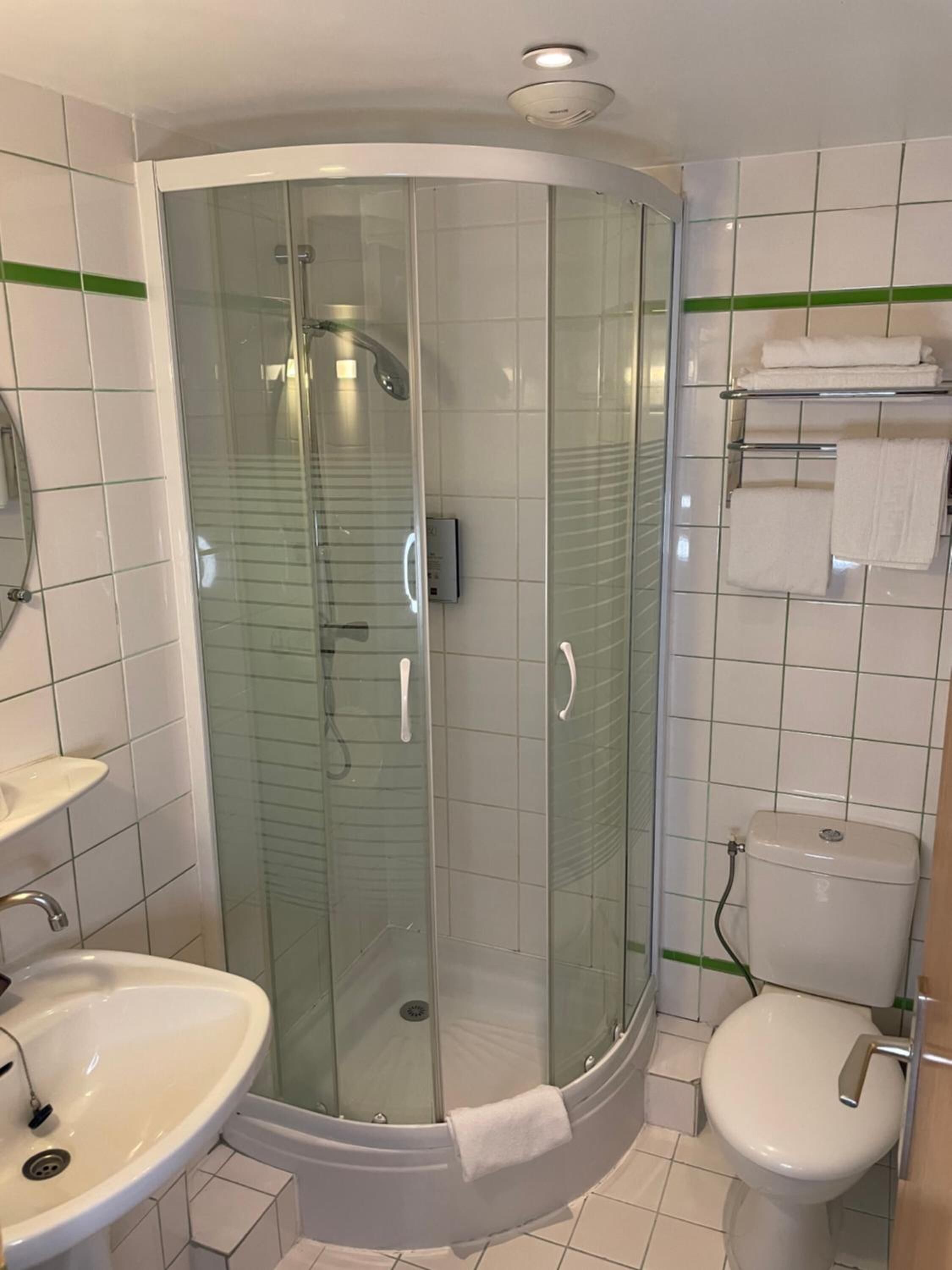 Une salle de bain moderne avec une douche à parois de verre, un lavabo et des toilettes.