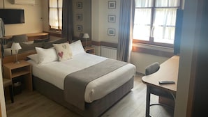 A hotel room with a large bed, bedside tables, a desk, a chair, a TV, and a window with curtains. - Hôtel Sainte Odile (Obernai)