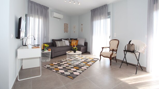 A modern living room with a sofa, a coffee table, a TV, and a small side table. - Edem apartment Sea View (Palaio Faliro)