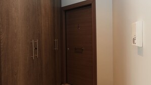 A closed wooden door with a handle and a lock, a small vent on the wall, and a tiled floor. - Edem apartment Sea View (Palaio Faliro)