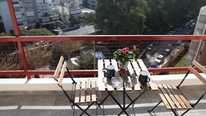 A balcony with a table, chairs, a potted plant, and a view of a cityscape. - Edem apartment Sea View (Palaio Faliro)