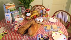 Una mesa de comedor con diversos alimentos, un jarrón de tulipanes y una silla.