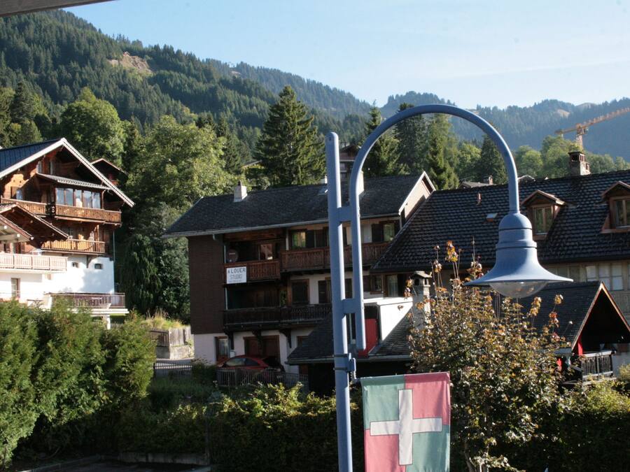 A mountain village with traditional wooden houses, a street lamp, and a sign for a studio.