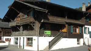 Un edificio de madera tradicional con un balcón, una escalera y un letrero que indica que es un restaurante.