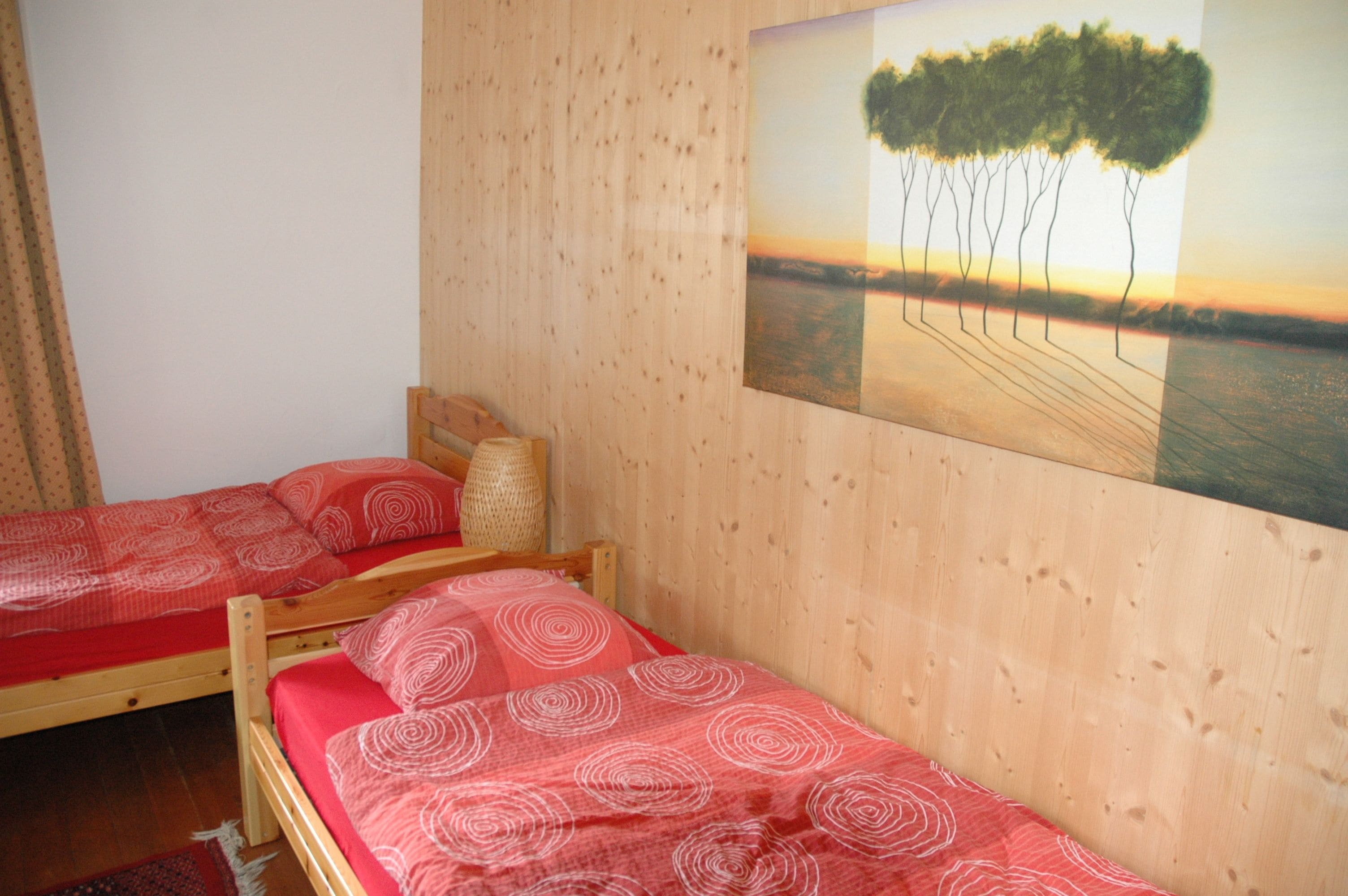 Un dormitorio con dos camas de madera, cabeceros de madera y un cuadro de árboles en la pared.