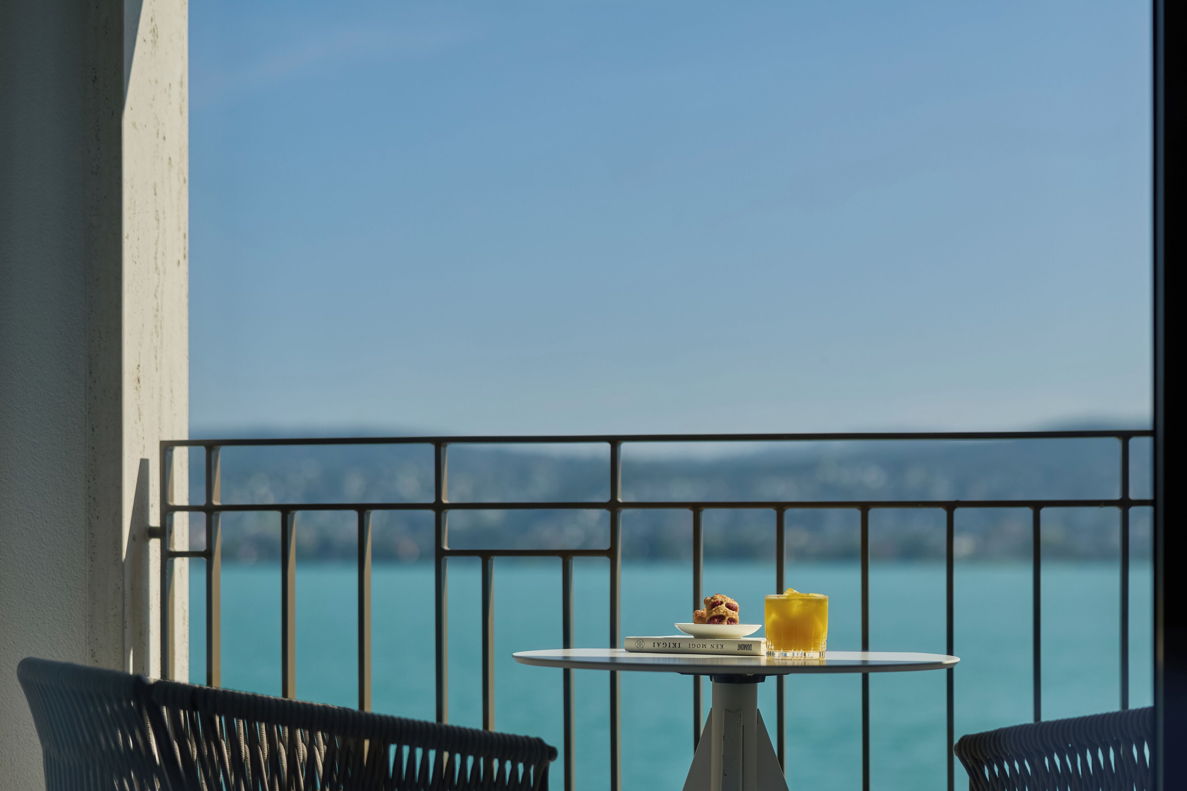 A balcony with a table, chairs, and a view of the sea.