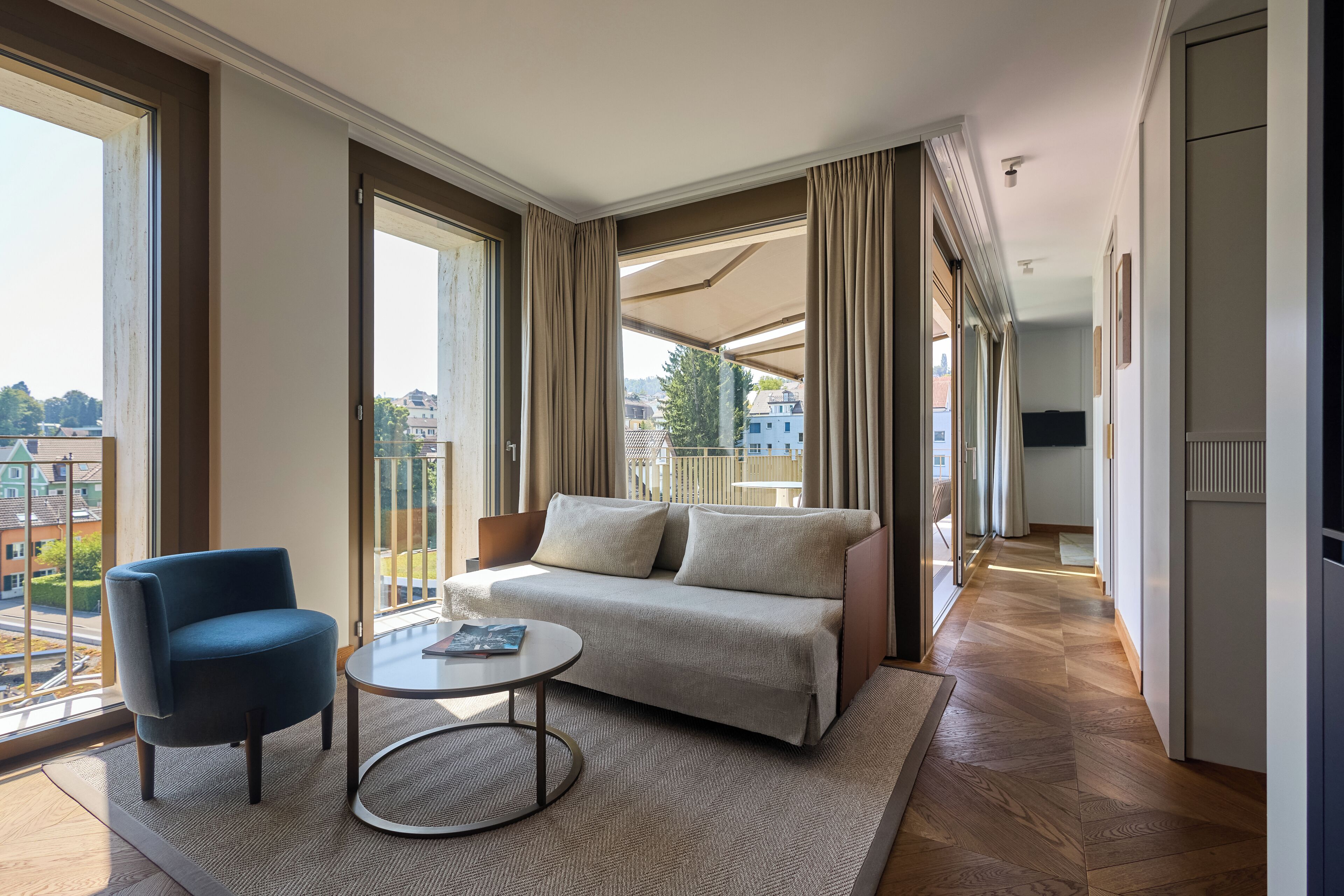 Une chambre d’hôtel moderne avec un canapé, un fauteuil et une table basse ronde.