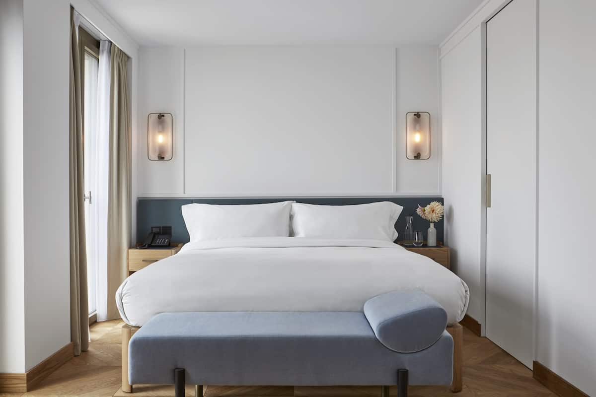 Ett modernt hotellrum med en stor säng, sängbord och en bänk.