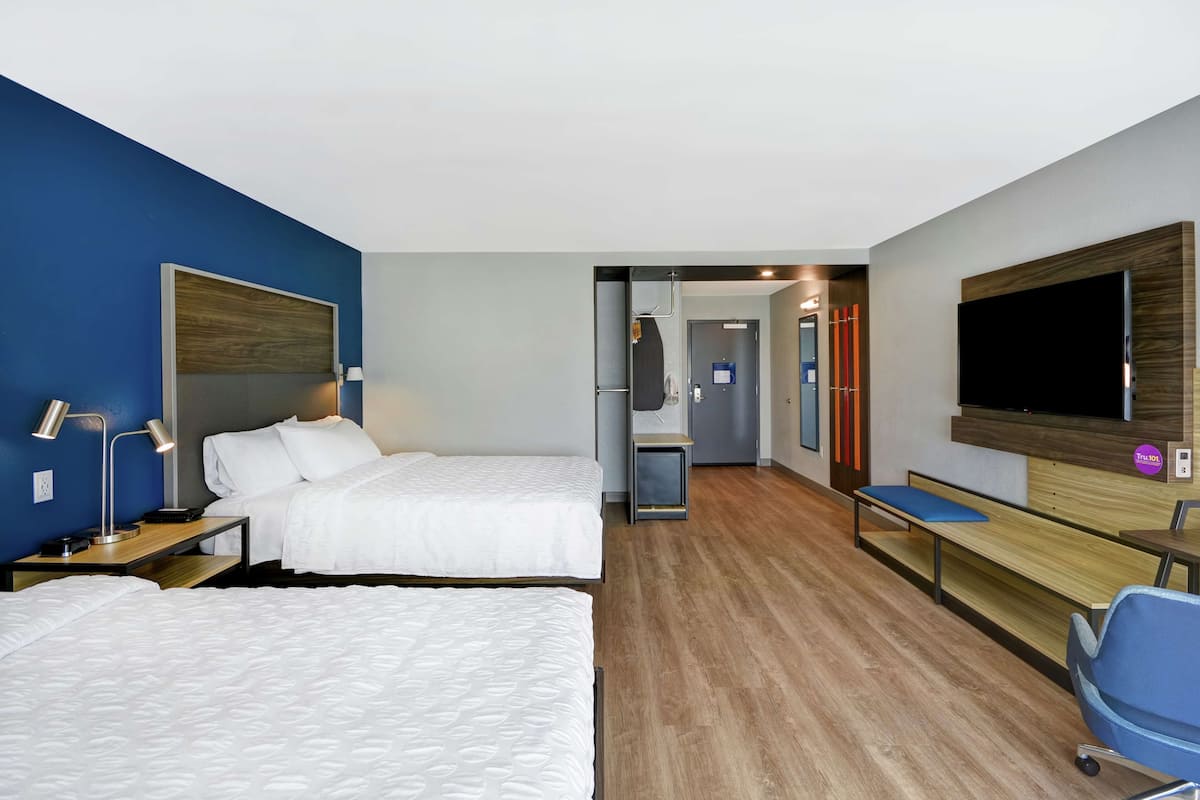 Habitació d'hotel amb dos llits, una televisió, escriptori i una cadira.