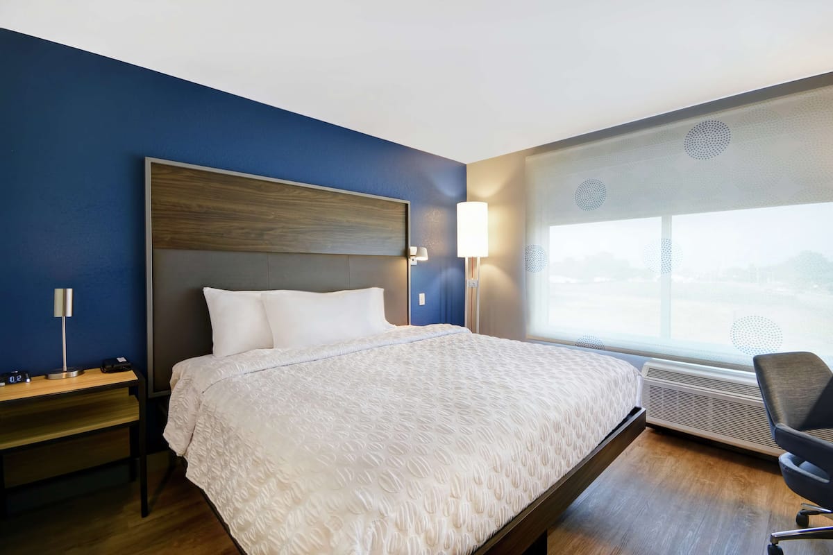 Una habitación de hotel moderna con una cama grande, mesitas de noche, un escritorio y una silla.